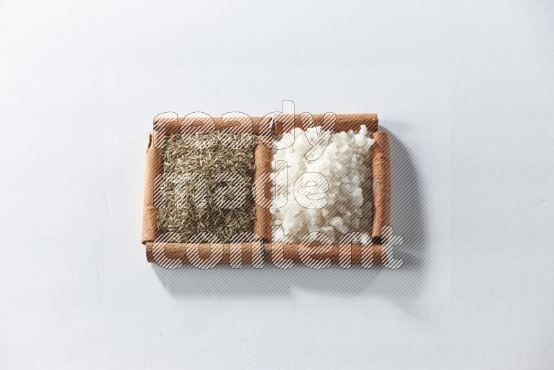 2 squares of cinnamon sticks full of white salt and cumin on white flooring