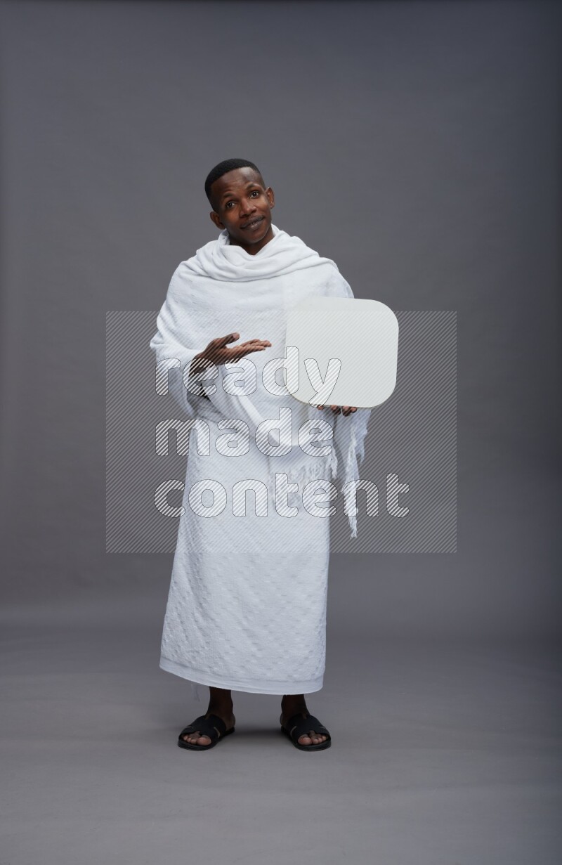 A man wearing Ehram Standing holding social media sign on gray background