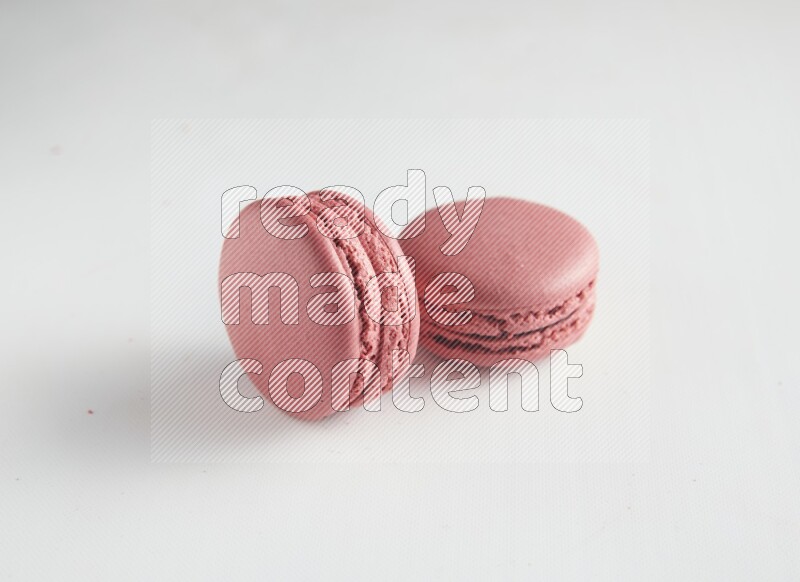 45º Shot of two Pink Raspberry macarons on white background