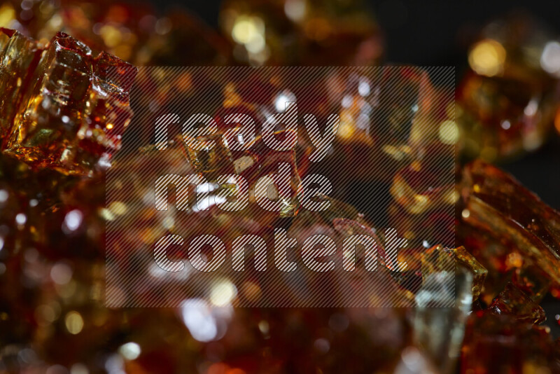 Transparent orange fragments of glass scattered on a black background