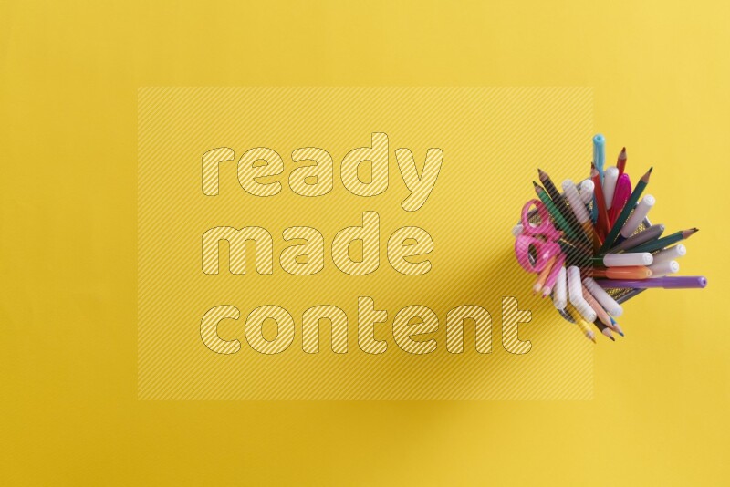 بعض الأقلام والمستلزمات المدرسية في مقلمة معدنية علي خلفية صفراء