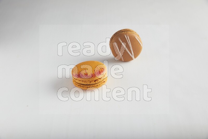 45º Shot of of two assorted Brown Irish Cream, and Orange Exotic macarons on white background