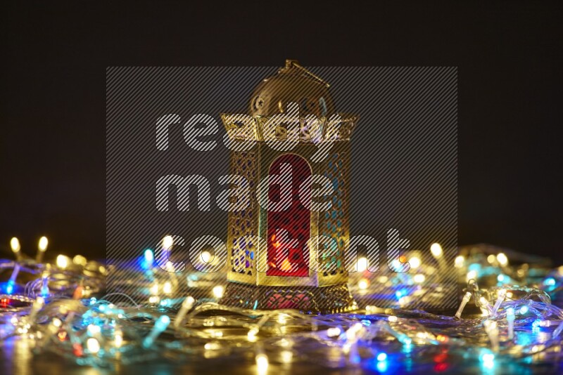 A traditional ramadan lantern surrounded by glowing fairy lights in a dark setup