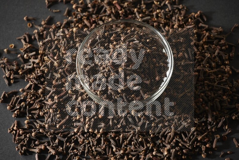 A glass bowl full of cloves on a black flooring