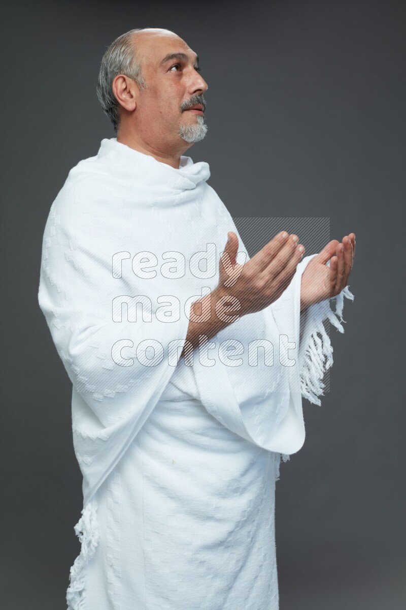 A man wearing Ehram Standing dua'a on gray background