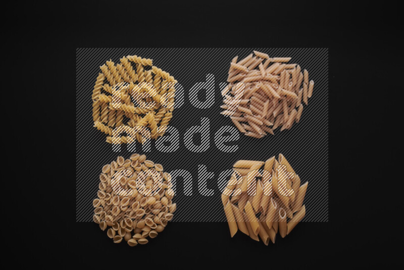 Different pasta types in bunches on black background