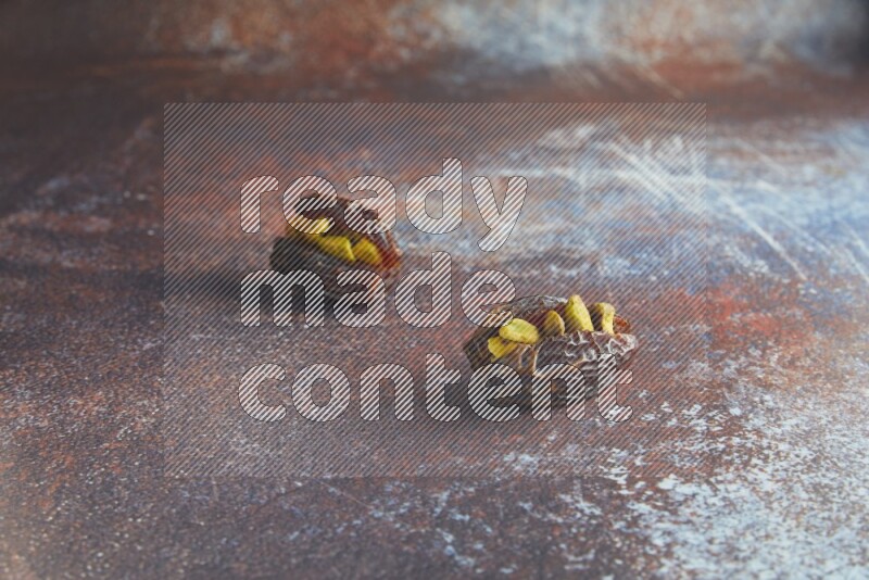 two pistachio stuffed madjoul dates on a rustic reddish background