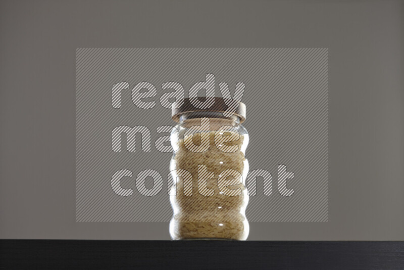 Basmati golden rice in a glass jar on black background
