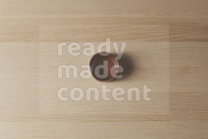 A brown pottery bowl on light wooden background
