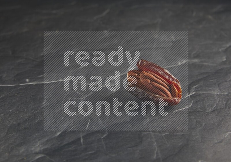 pecan stuffed madjoul date on a black textured background