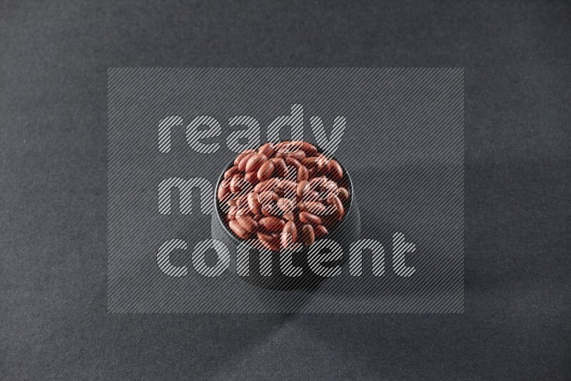 وعاء فخاري أسود ممتلئ بالفول السوداني على خلفية سوداء