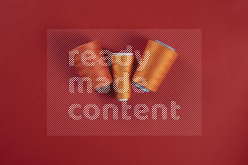 An orange collection of sewing and tailoring tools arranged on a red background