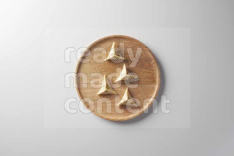 Four Sambosas on a wooden round plate on a white background