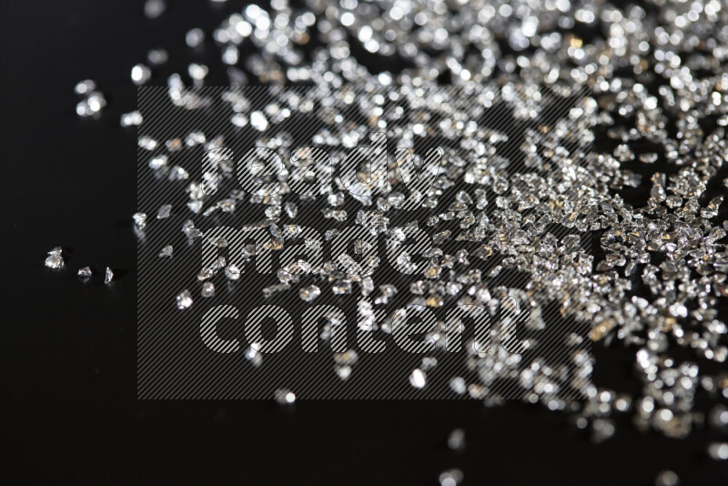 Silver shimmering fragments of glass scattered on a black background