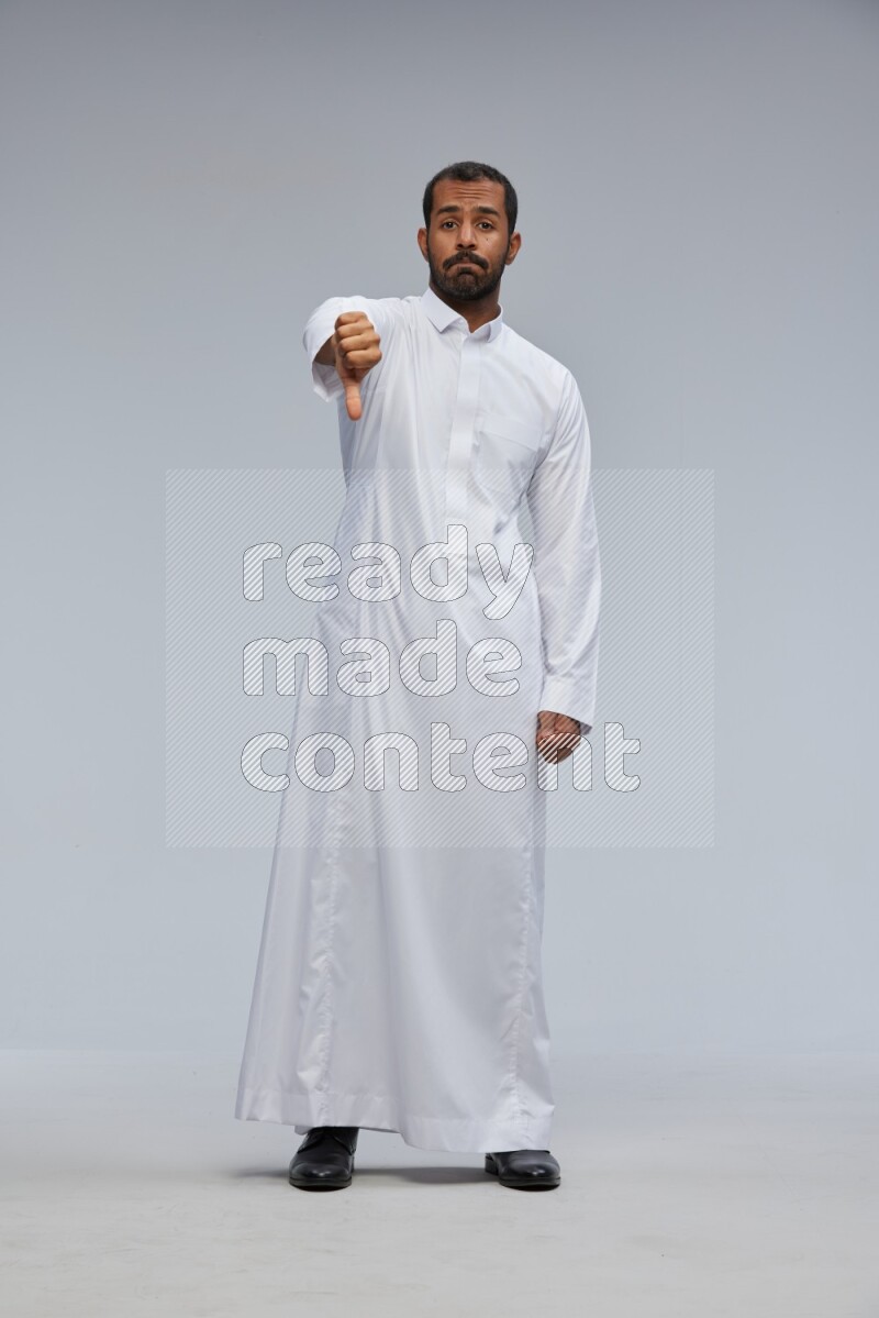 Saudi man Wearing Thob standing interacting with the camera on Gray background