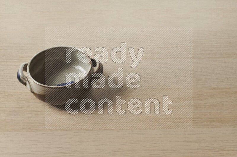 A multicolored pottery bowl on light wooden background