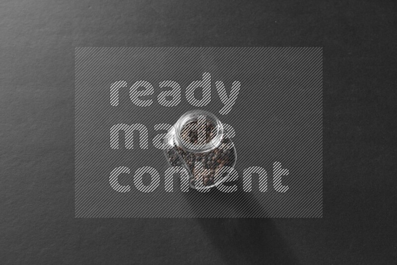 فلفل أسود في وعاء زجاجي علي خلفية سوداء