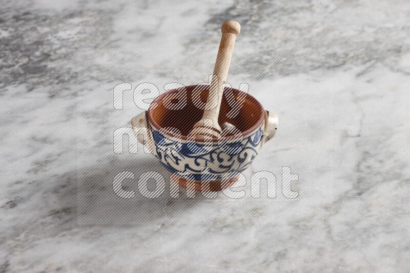 Decorative pottery pot with wooden honey dipper in it on grey marble background