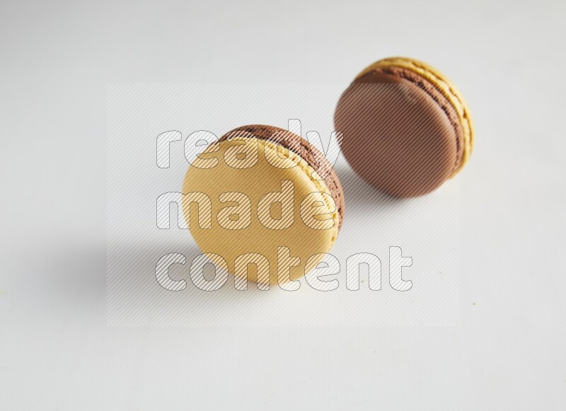 45º Shot of two Yellow and Brown Chai Latte macarons on white background