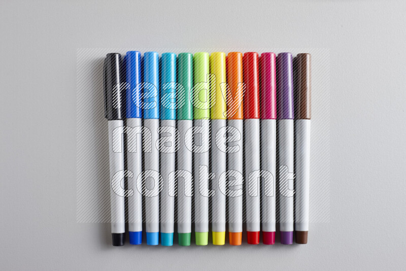 An arrangement of coloring pens in different colors on grey background