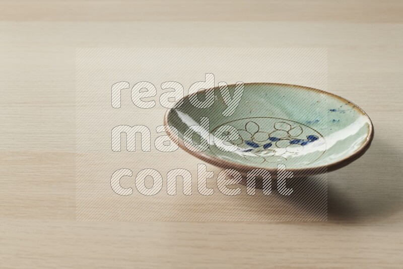 A decorative pottery plate on light wooden background
