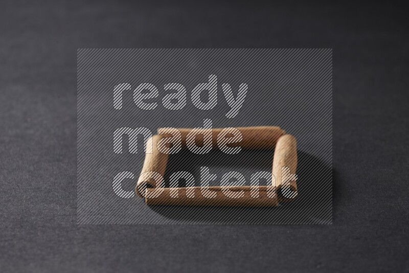 أربعة من أعواد القرفة مكونة شكل مربع فارغ علي خلفية سوداء