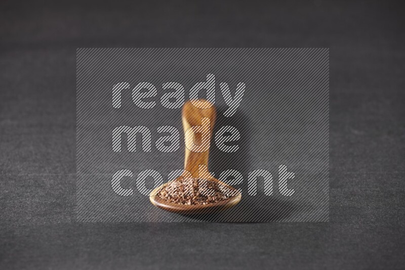 ملعقة خشبية كبيرة ممتلئة بحبوب بذر الكتان علي خلفية سوداء