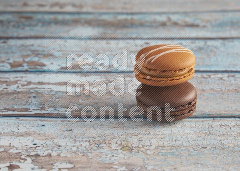 45º Shot of of two assorted Brown Irish Cream, and Brown Dark Chocolate macarons on light blue background