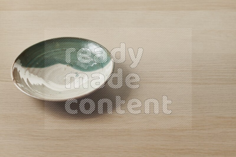A multicolored pottery plate on light wooden background