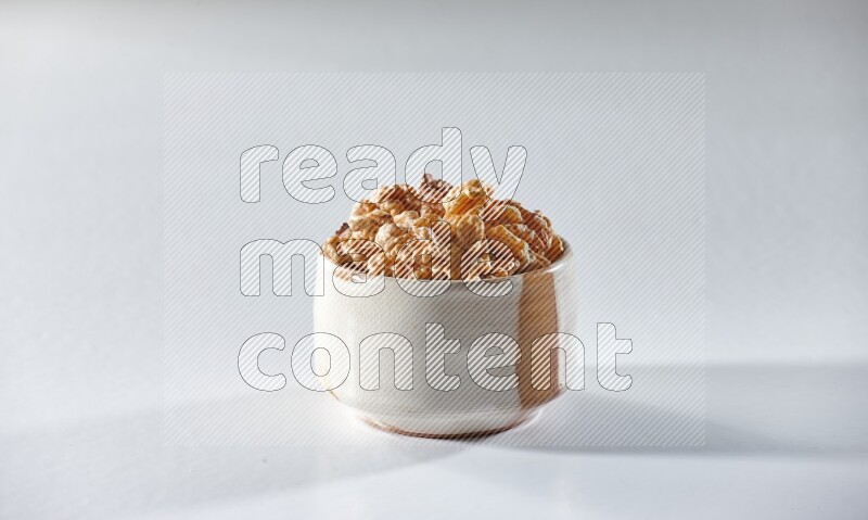 A beige ceramic bowl full of peeled walnuts on a white background in different angles