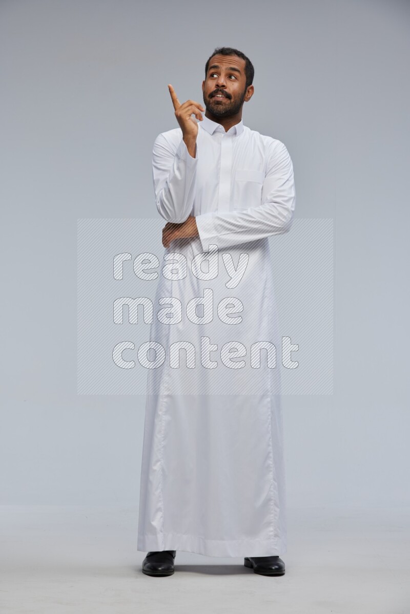 Saudi man Wearing Thob standing interacting with the camera on Gray background