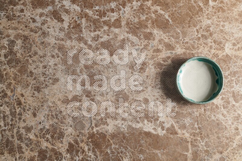 A multicolored pottery bowl on beige marble background