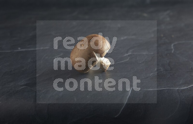 45 degre cremini  mushrooms on a textured black slate background
