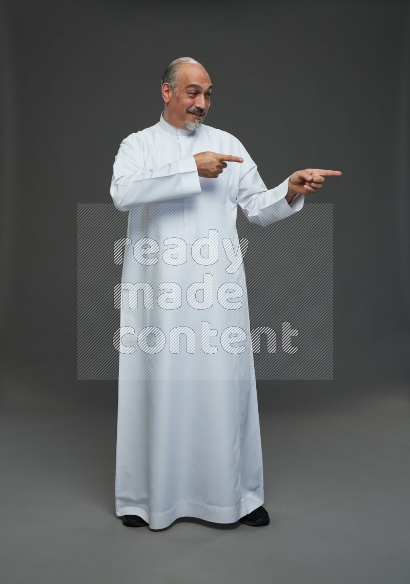 Saudi man without shomag Standing Interacting with the camera on gray background