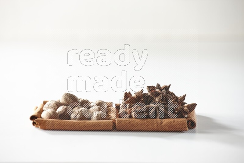 مربعان من أعواد القرفة ممتلئان باليانسون النجمي وجوزة الطيب علي خلفية بيضاء