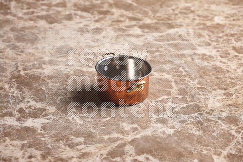 A small copper pot on beige marble background