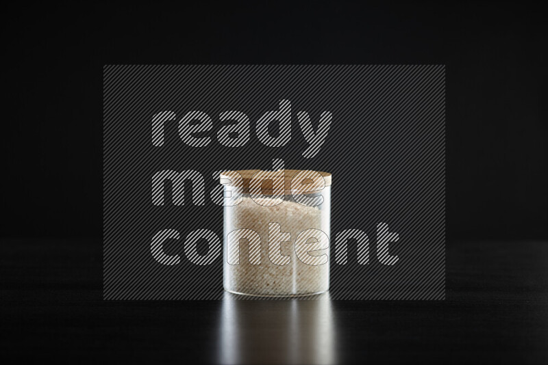 White rice in a glass jar on black background