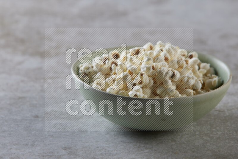 popcorn in green bowl on a grey textured countertop