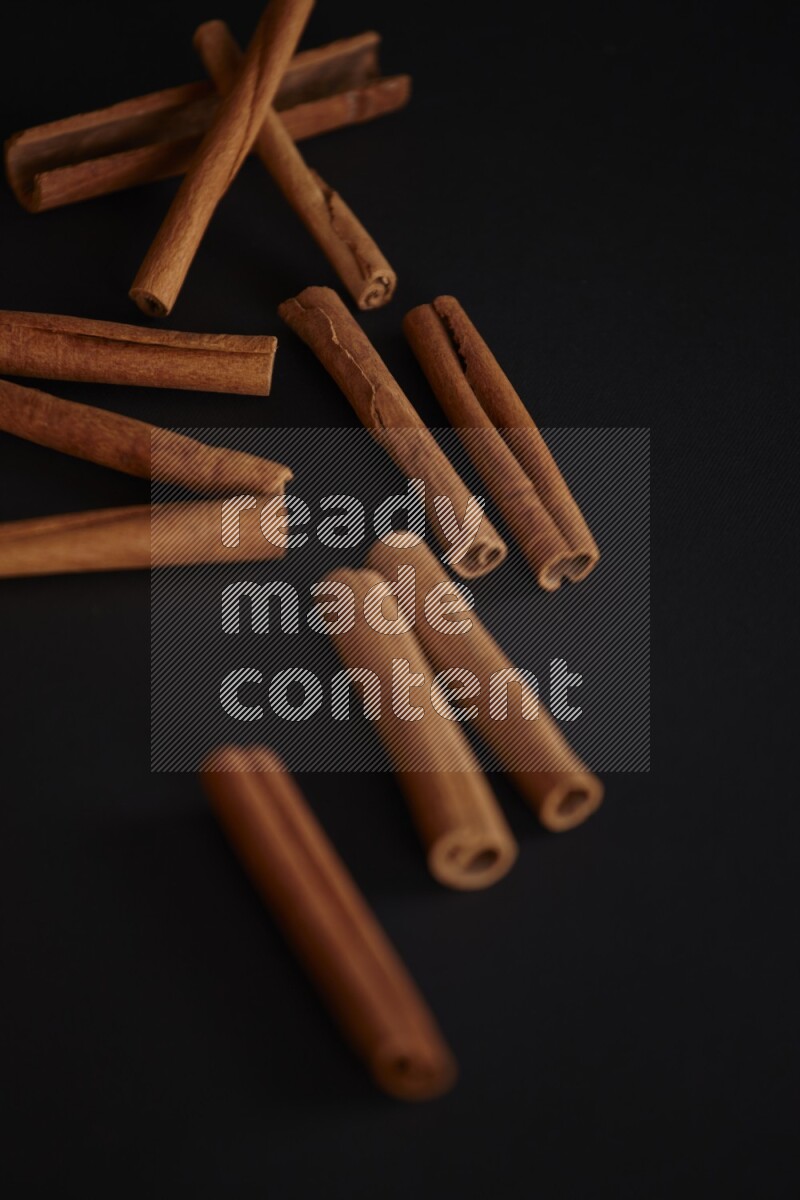 Cinnamon sticks stacked on black flooring
