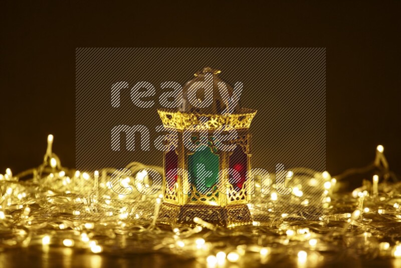A traditional ramadan lantern surrounded by glowing fairy lights in a dark setup