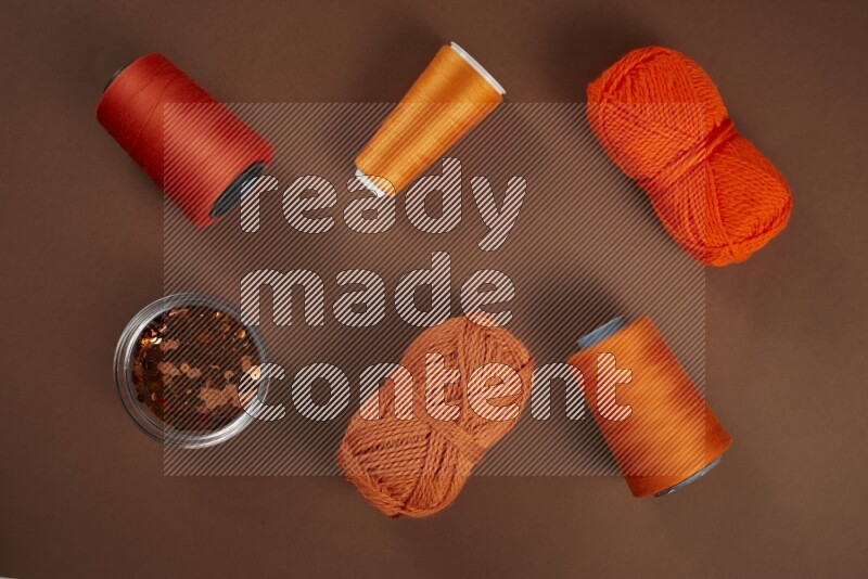 An orange collection of sewing and tailoring tools arranged on a brown background