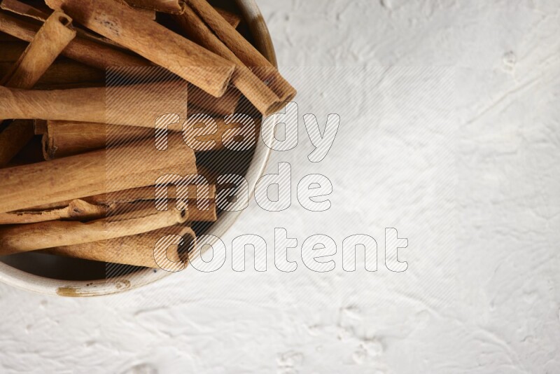 Cinnamon sticks in a ceramic bowl in different angles on white background