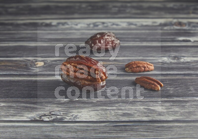 two pecan stuffed madjoul date on a wooden grey background