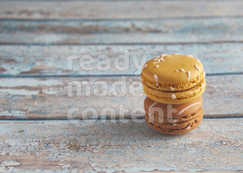 45º Shot of of two assorted Brown Irish Cream, and Yellow Piña Colada macarons on light blue background