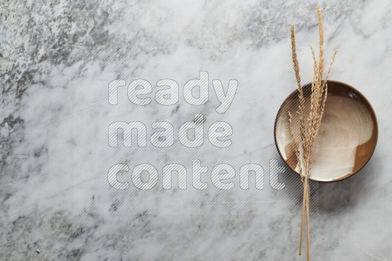 Wheat stalks on multicolored pottery plate on grey marble background
