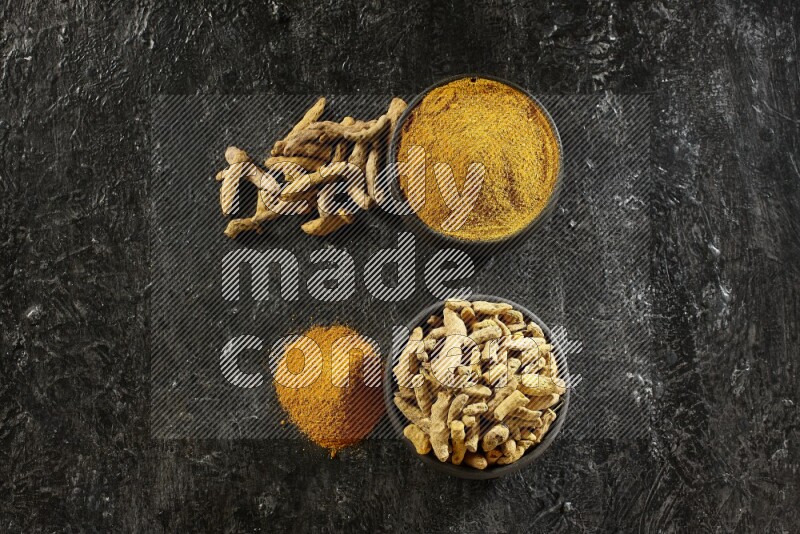 وعاءان من الفخار باللون الأسود، أحدهما ممتلئ ببودرة الكركم والآخر ممتلئ بأصابع كاملة من الكركم المجفف على خلفية سوداء