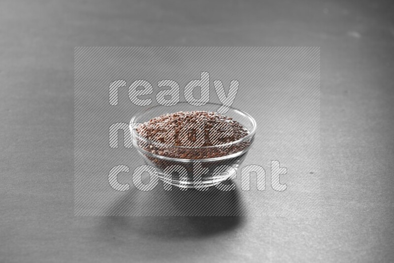 A glass bowl full of flax on black flooring