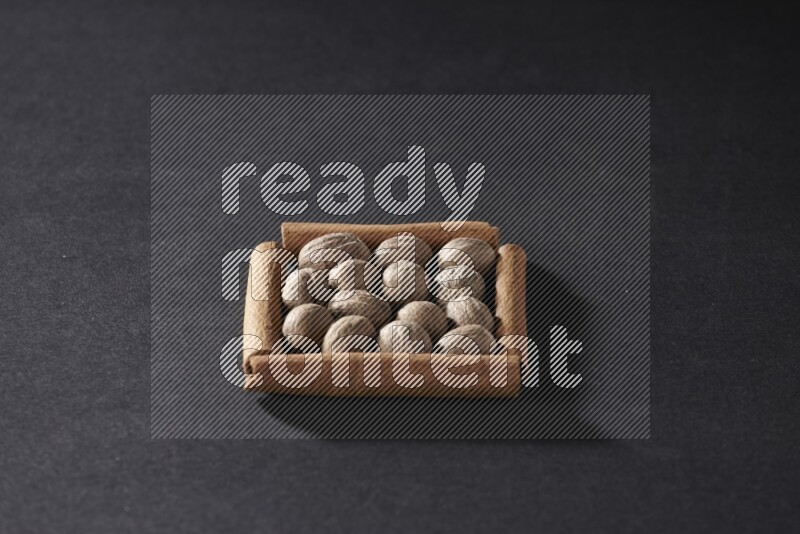 A single square of cinnamon sticks full of nutmeg on black flooring