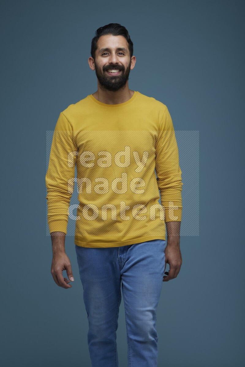 Man posing in a blue background wearing a yellow shirt