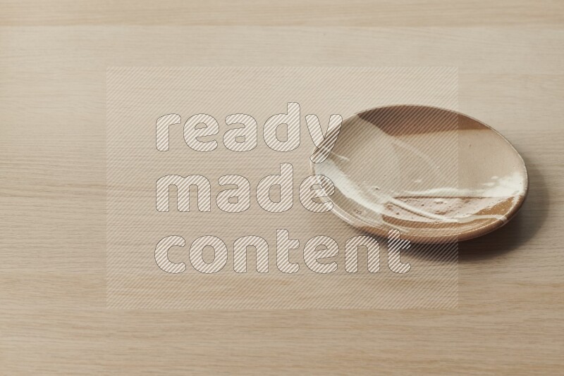 A beige pottery plate on light wooden background